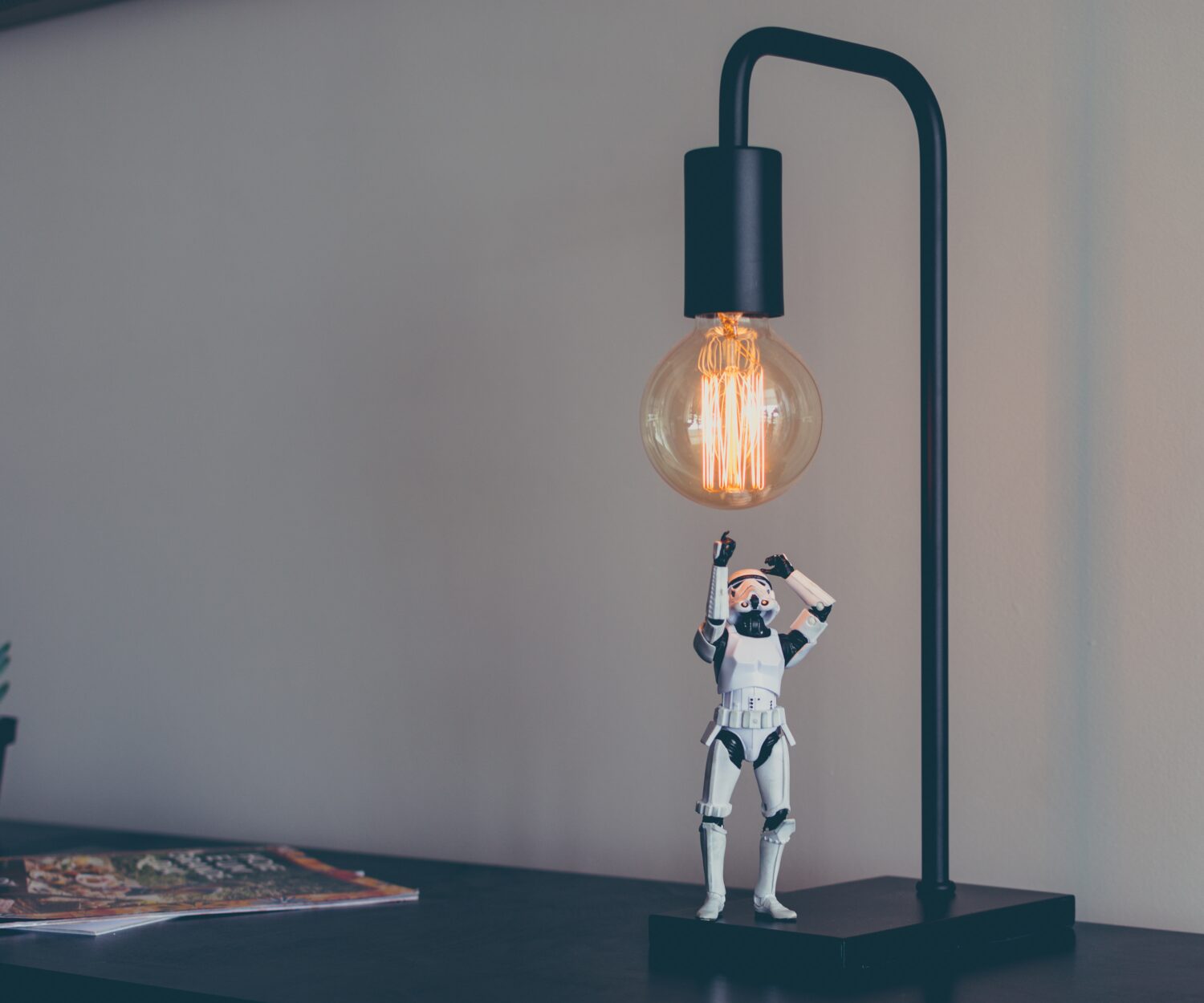 Ein Stormtrooper-Spielfigur greift nach einer Glühbirne. Auf einem Schreibtisch