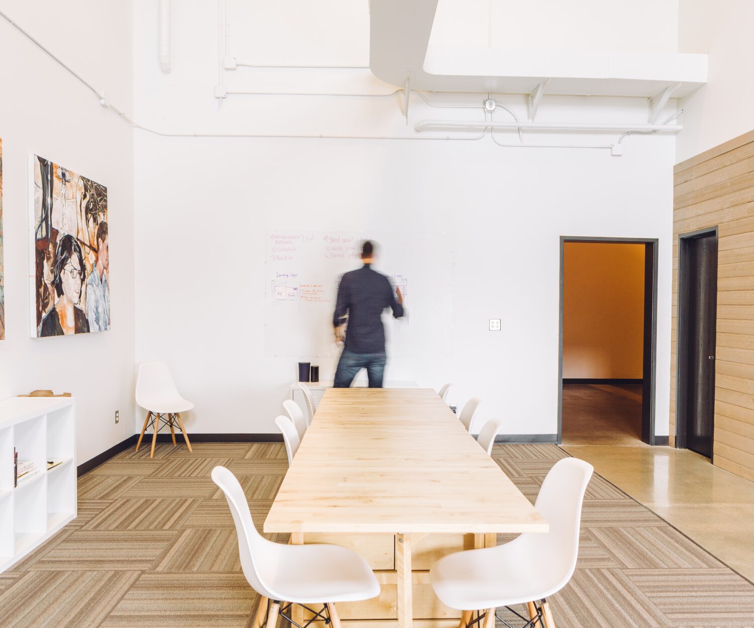 Ein Mann arbeitet allein in einem weißen Meetingraum. Er schreibt auf ein Whiteboard. Schehmeneffekt zeigt, dass er ganz viel arbeitet